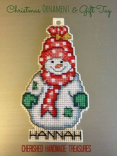 a cross stitch christmas ornament and gift tag with a snowman on it