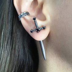 a pair of ear piercings with two skulls and a cross on each one side