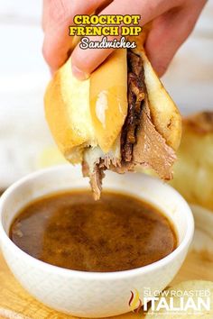 a hand holding a sandwich over a bowl of soup