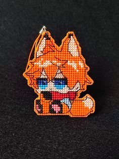 an orange and white pixelated animal keychain on a black surface