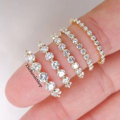 a hand holding five different sized diamond rings