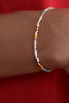 a woman's arm wearing a bracelet with multicolored beads and gold accents