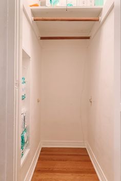 an empty white closet with wood floors and shelves