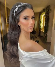 a woman with long hair wearing a white dress and tiara in front of a mirror