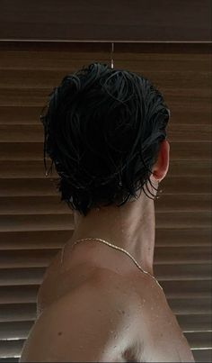 the back of a man's head in front of a window covered with blinds