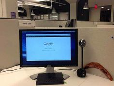 a desktop computer sitting on top of a white desk in an office cubicle,