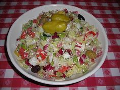 a white bowl filled with salad on top of a red and white checkered table cloth