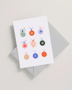 a card with christmas ornaments on it sitting on top of an envelope next to a piece of paper