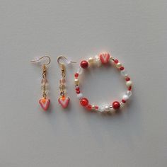 Here is a set of strawberry themed earrings and bracelet ⋆˚｡｡⋆ The colors are mainly white and red; The earrings measure 5.5 centimeters in length in total. Stretched, the bracelet can be approximately 18 centimeters in diameter, unstretched as it is in the photo it is approximately 8 centimeters in diameter. To make this set I used glass beads, plastic beads, elastic wire, metal rods, gold buckles, polymer clay beads and seed beads!! The glass beads have a beautiful effect with the light :) ️🕯 Red Dangle Bracelets As Gift, Cute Round Red Jewelry, Cute Red Bracelet Jewelry, Cute Red Round Jewelry, Trendy Red Jewelry With Heart Beads, Casual Red Jewelry With Heart Beads, Strawberry Bead Bracelet, Beaded Strawberry Bracelet, Fruit Bracelet Strawberry Clay Beads