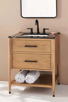 a bathroom vanity with two drawers and a mirror on the wall above it, along with white towels