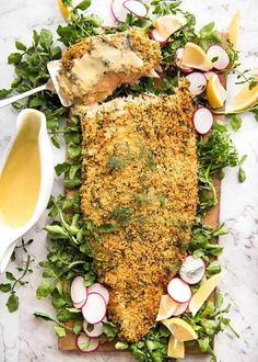 a fish fillet is on a cutting board with radishes and lemon wedges