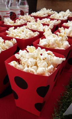 red paper cups filled with popcorn sitting on top of a table covered in black and white polka dots