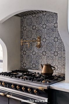 a stove top oven sitting inside of a kitchen next to a wall covered in blue and white tiles