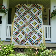 a multicolored quilt hanging on the front porch