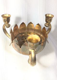 an ornate brass candle holder with three candles in it's center, on a white background