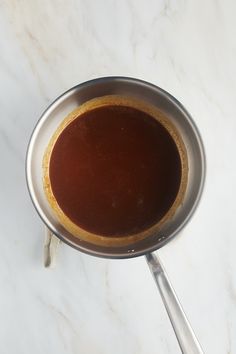 the sauce is being stirred in a pan with tongs on a marble counter top