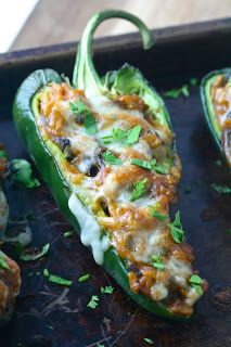 three stuffed green peppers on a baking sheet