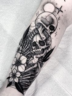 a black and white photo of a skull with flowers on it's arm,