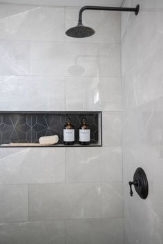 a bathroom with a shower head, soap dispenser and two bottles on the shelf