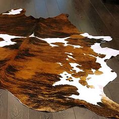 a brown and white cowhide rug on a wooden floor