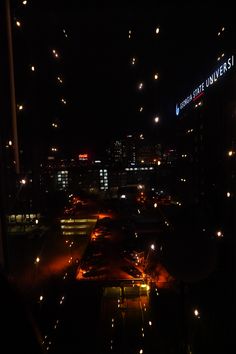 fireworks are lit up in the night sky above an urban area with buildings and street lights