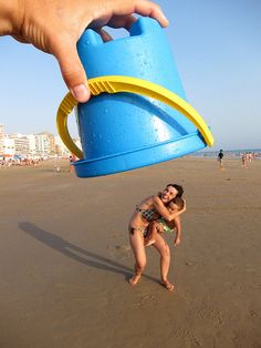 a child is playing on the beach with a blue water jug