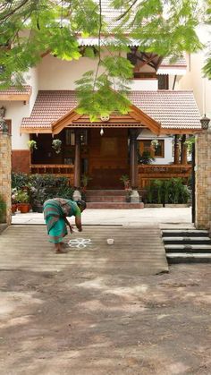 a woman is washing her hands in front of a house with steps leading up to it