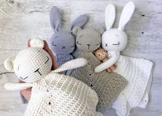 three crocheted stuffed animals laying next to each other on a white wooden surface