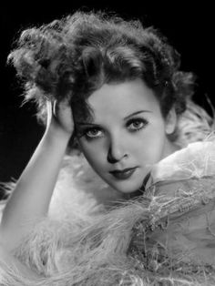 a black and white photo of a woman with her hair in a feathered coat