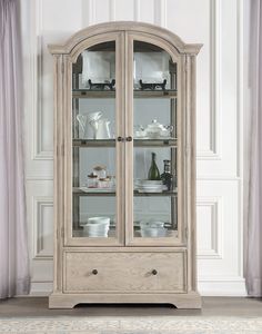 a white china cabinet with glass doors and drawers