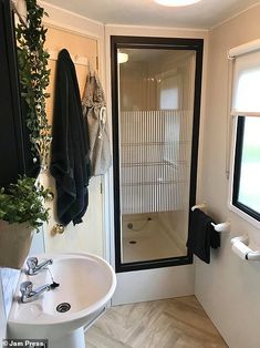 a white sink sitting under a bathroom mirror next to a walk in shower and toilet