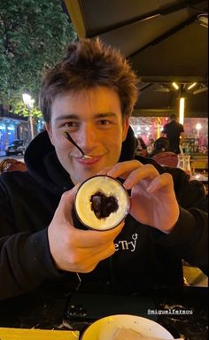 a man holding up a drink in front of his face and smiling at the camera