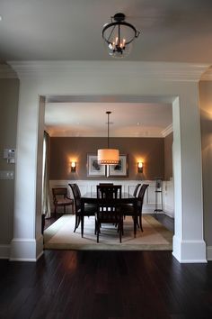 a dining room table and chairs in front of a light fixture with two lamps on each side