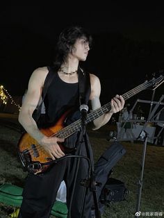 a young man playing an electric guitar in front of a microphone and keyboard on the grass