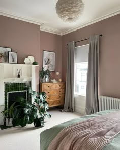 a bedroom with pink walls and a fireplace in the corner, along with pictures on the wall