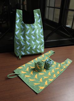 a green and yellow bag sitting on top of a wooden table next to two cups