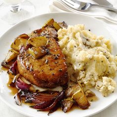 a white plate topped with meat, potatoes and gravy next to a fork