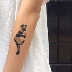 a woman's arm with a small tattoo of a raccoon on it