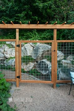 a wooden gate with metal wire and rocks behind it