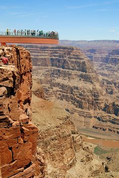 people are standing on the edge of a cliff and looking out at the canyon below