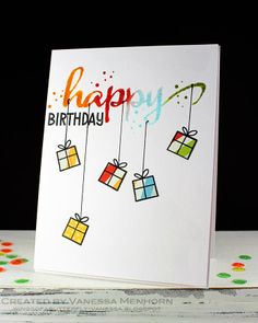 a happy birthday card with gift boxes hanging from strings and confetti sprinkles