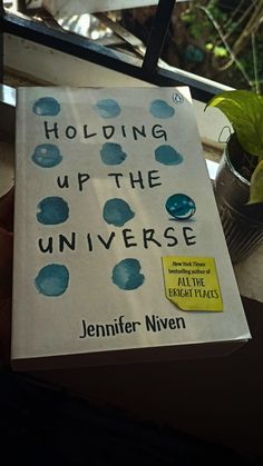 the book holding up the universe by jennifer niven is in front of a window