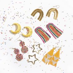 several pairs of earrings and ear clips on a white surface with confetti sprinkles