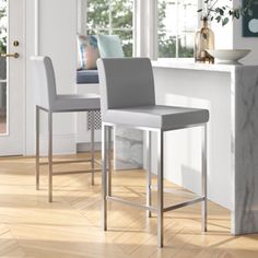 two gray and white bar stools sitting in front of a counter