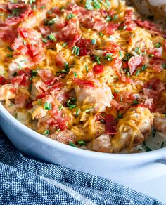 a casserole dish with chicken, cheese and tomatoes in it on a blue towel