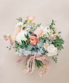 a bridal bouquet with pink, white and blue flowers on the top is hanging from a wall