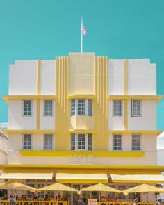 people are sitting at tables in front of a yellow and white building