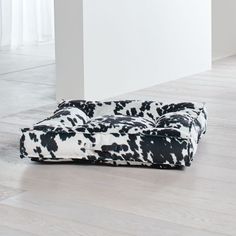 a black and white cow print couch sitting on top of a hard wood floor next to a wall