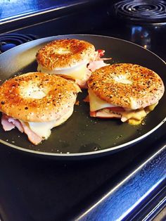 two bagels with ham and cheese on them sitting on a pan in the oven