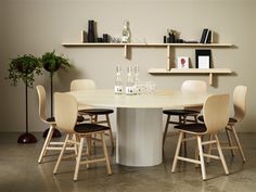 a round table with chairs around it and shelves on the wall in the back ground